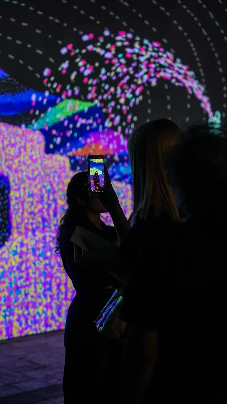 A visitor photographs a colourful digital projection.